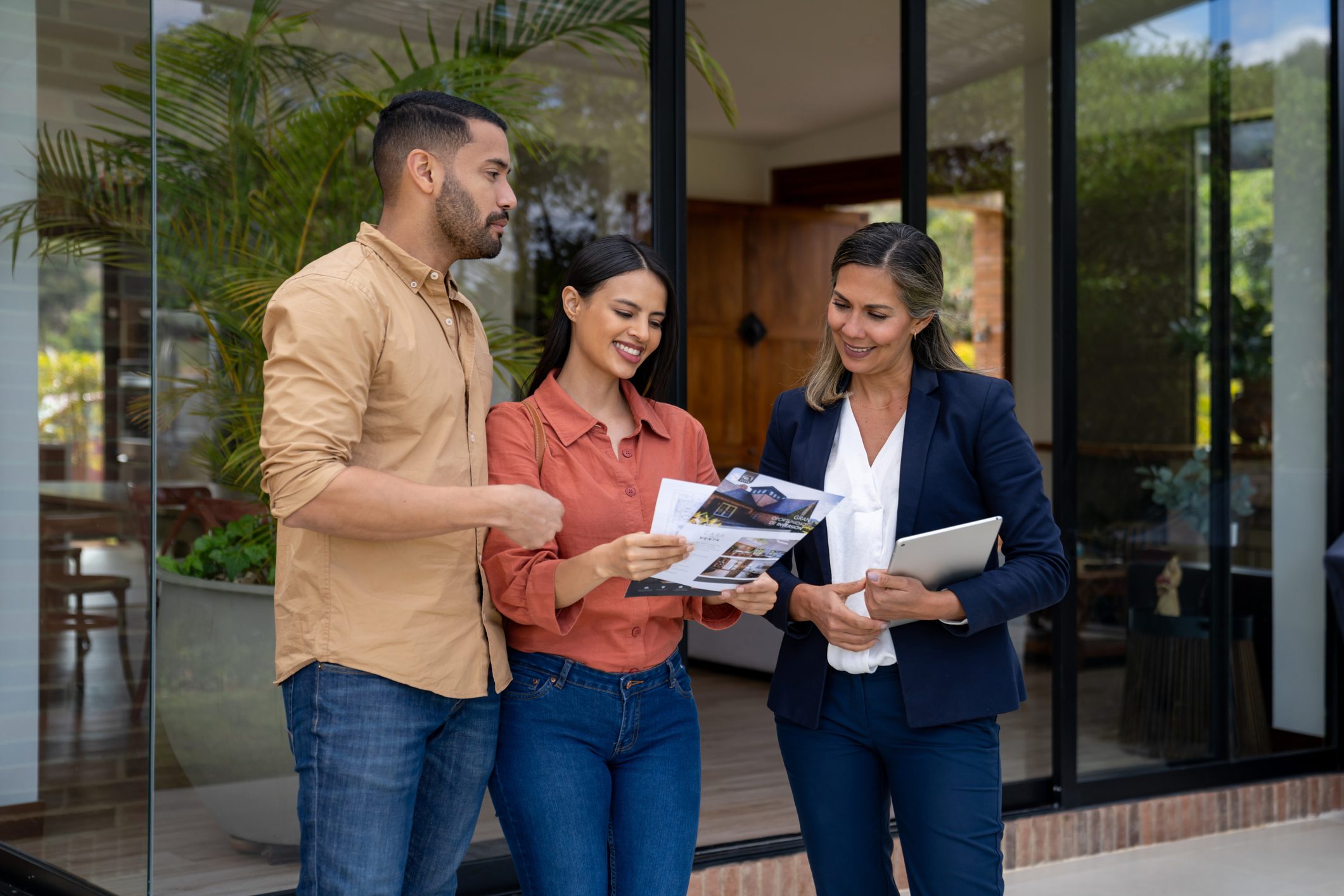 Couple discussing documents with businesswoman outside.